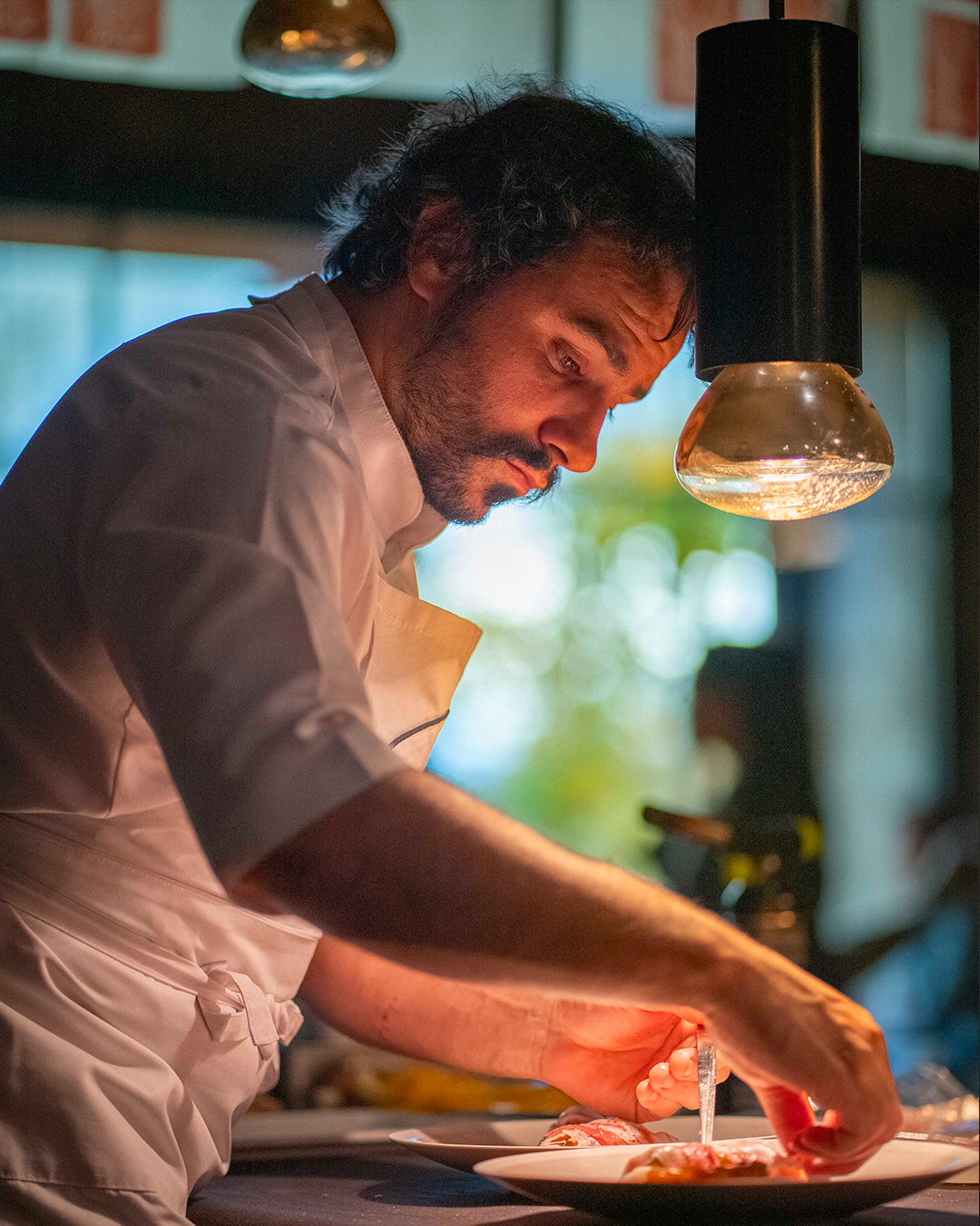 Léo Troisgros en train de dresser une assiette avec au dessus une lampe chauffante sur mesure