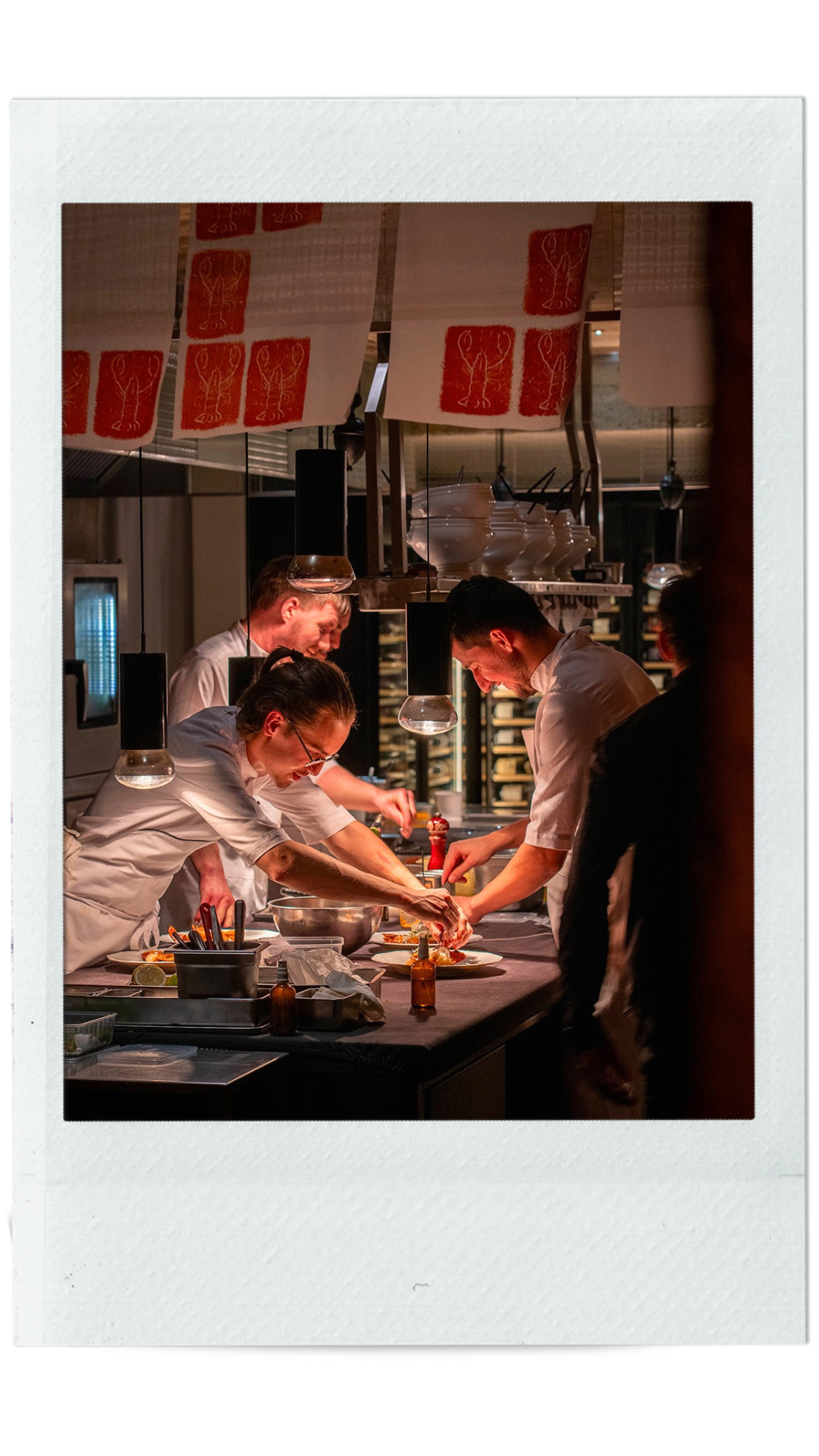 Plusieurs cuisiniers dans la cuisine de la La colline du Colombier sous lampes chauffantes sur mesure réalisées par l'Atelier Eleven.