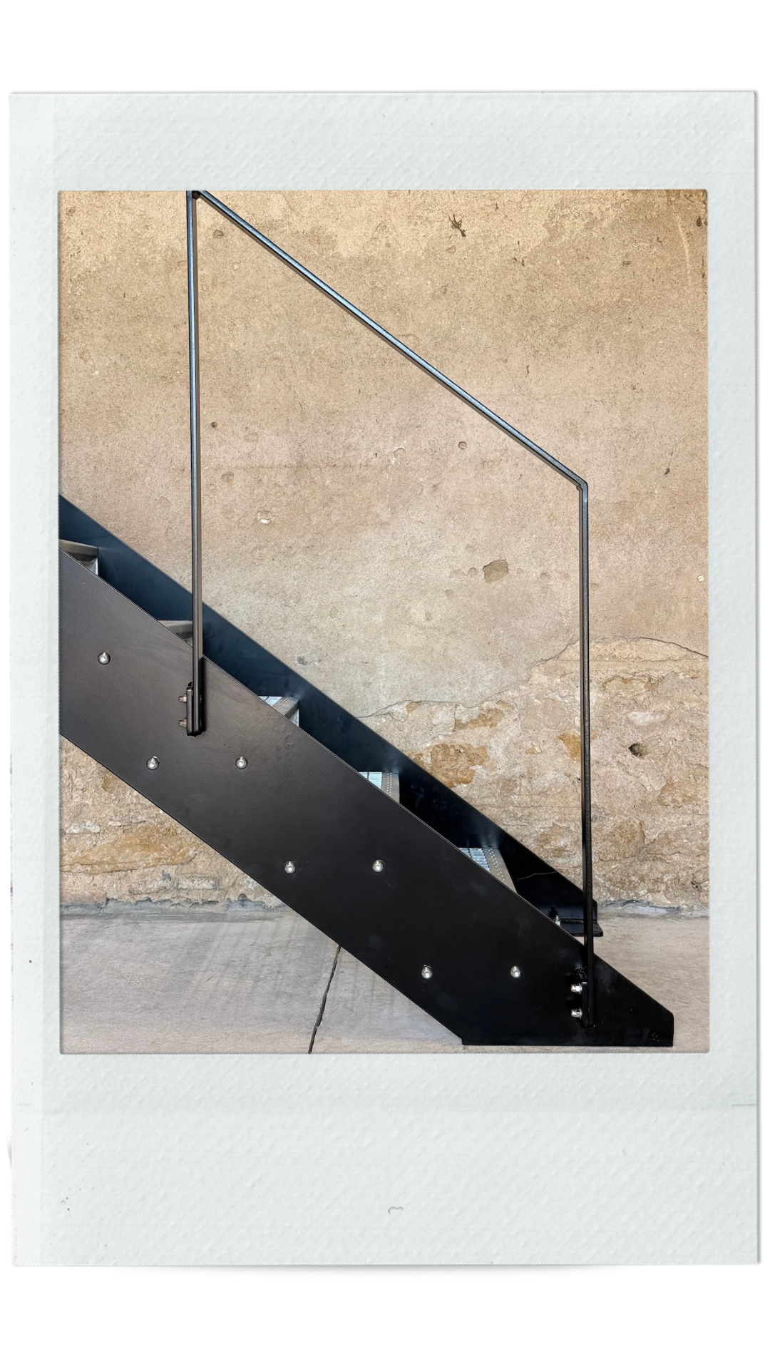 Escalier en métal 2 limons extérieur peint en noir. Vue de côté détail du bas de l'escalier